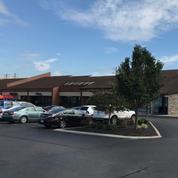 exterior of commercial complex building and a parking lot with cars and a tree